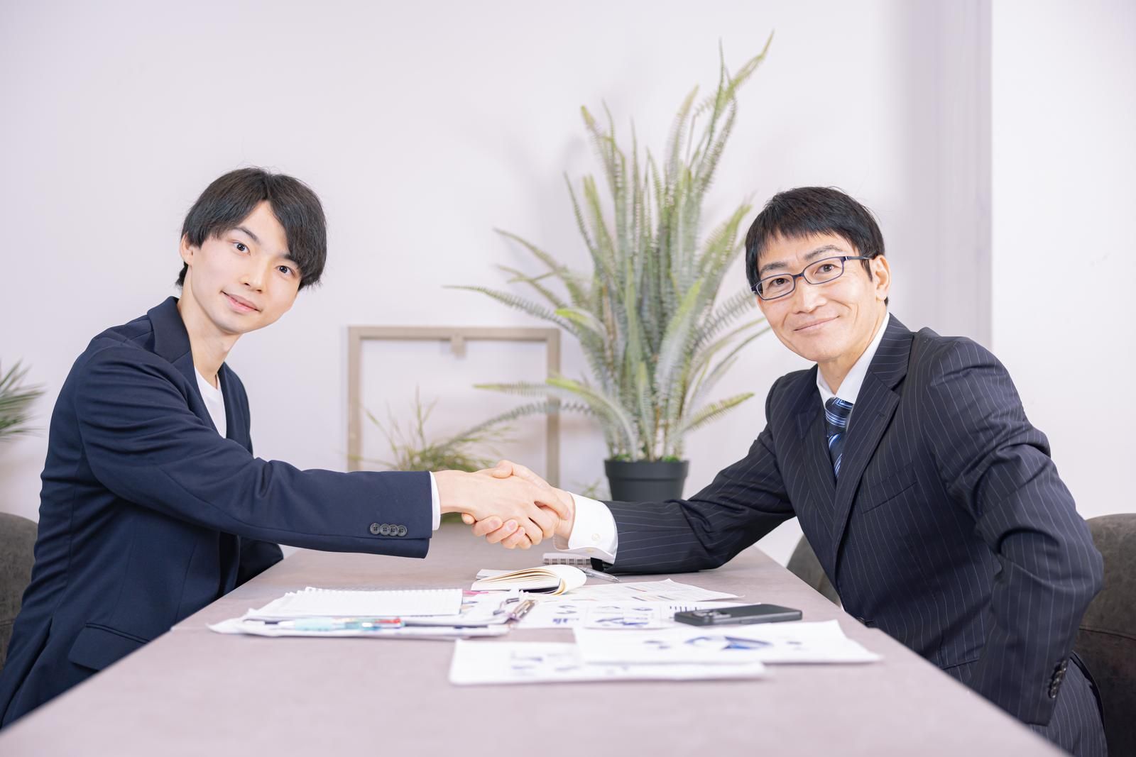 部長と若手男性社員が握手を交わす様子